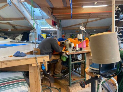 Opérateur de couture travaillant sur une voile dans notre atelier de voilerie à Cherbourg