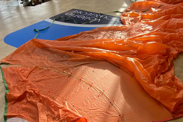 Voile orange déployée sur le plancher de notre atelier de voilerie à Cherbourg pour fabrication et réparation sur mesure