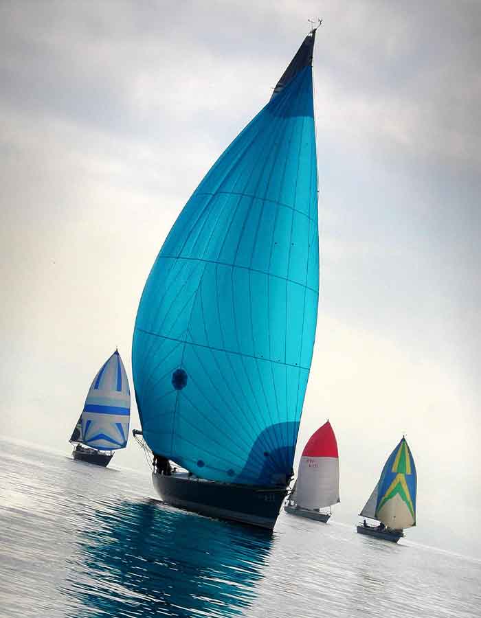 Gennaker bleu sur mesure déployé en mer pendant une régate, offrant puissance et performance au voilier